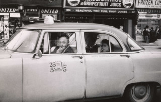Taxicab driver at the wheel with two passengers, N.Y.C. 1956.